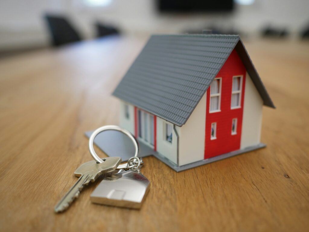 Model house with red accents and keys on a wooden table, representing real estate transactions and 1099 filing requirements for real estate agents.