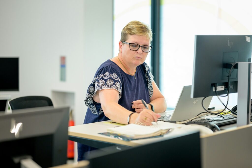 Woman working at a desk with a computer, taking notes, illustrating efficiency and focus for tax professionals using 1099 filing software.